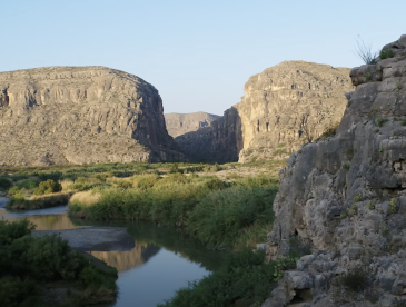 View of a river winding through rocky outcrops with a clear blue sky.